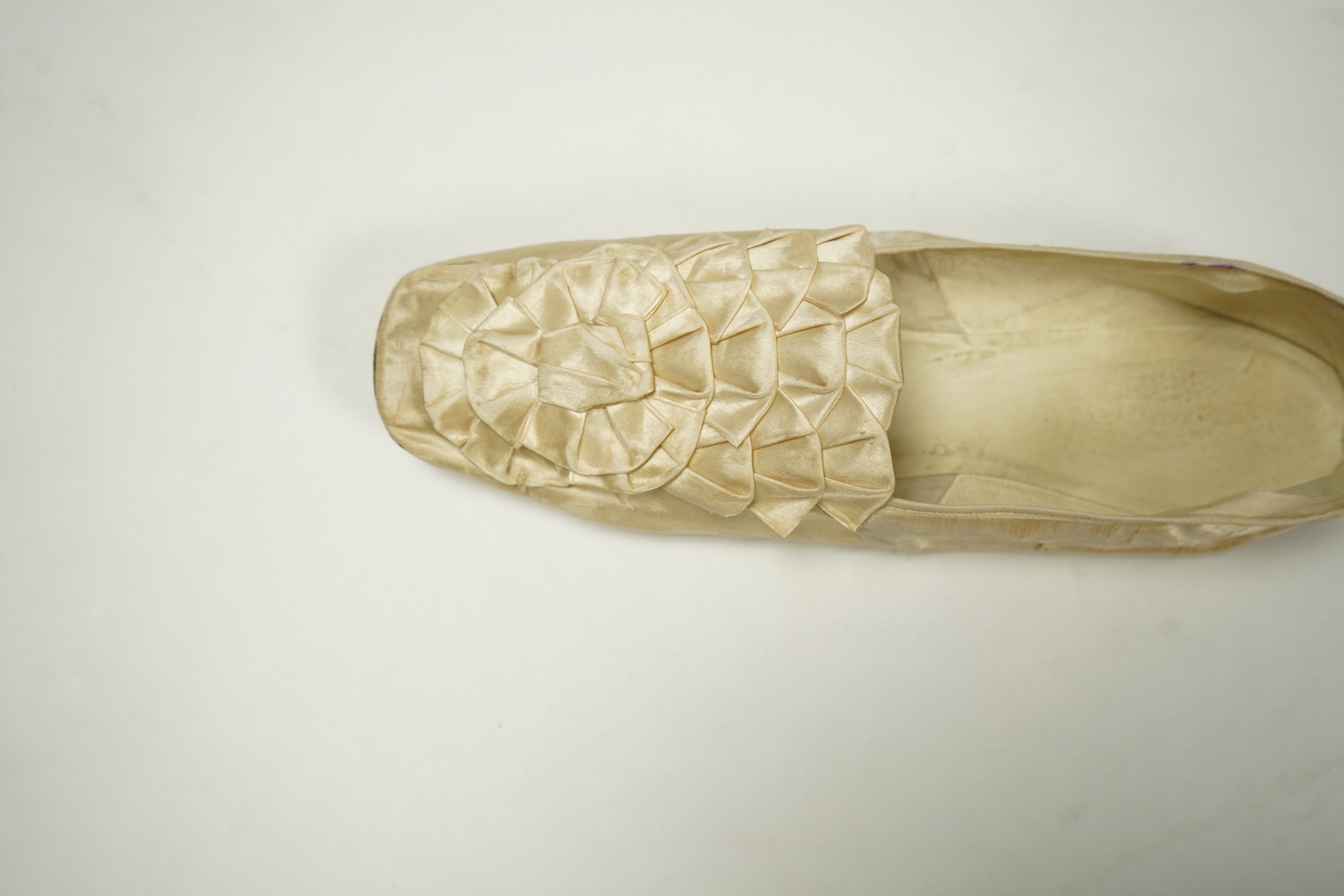 A 19th century hand made cream kid leather ladies ankle boot and four differing cream silk and satin single wedding shoes. All with leather soles. Possibly a traveller's sample range. Boots 24.5cm long (heel to toe). Con